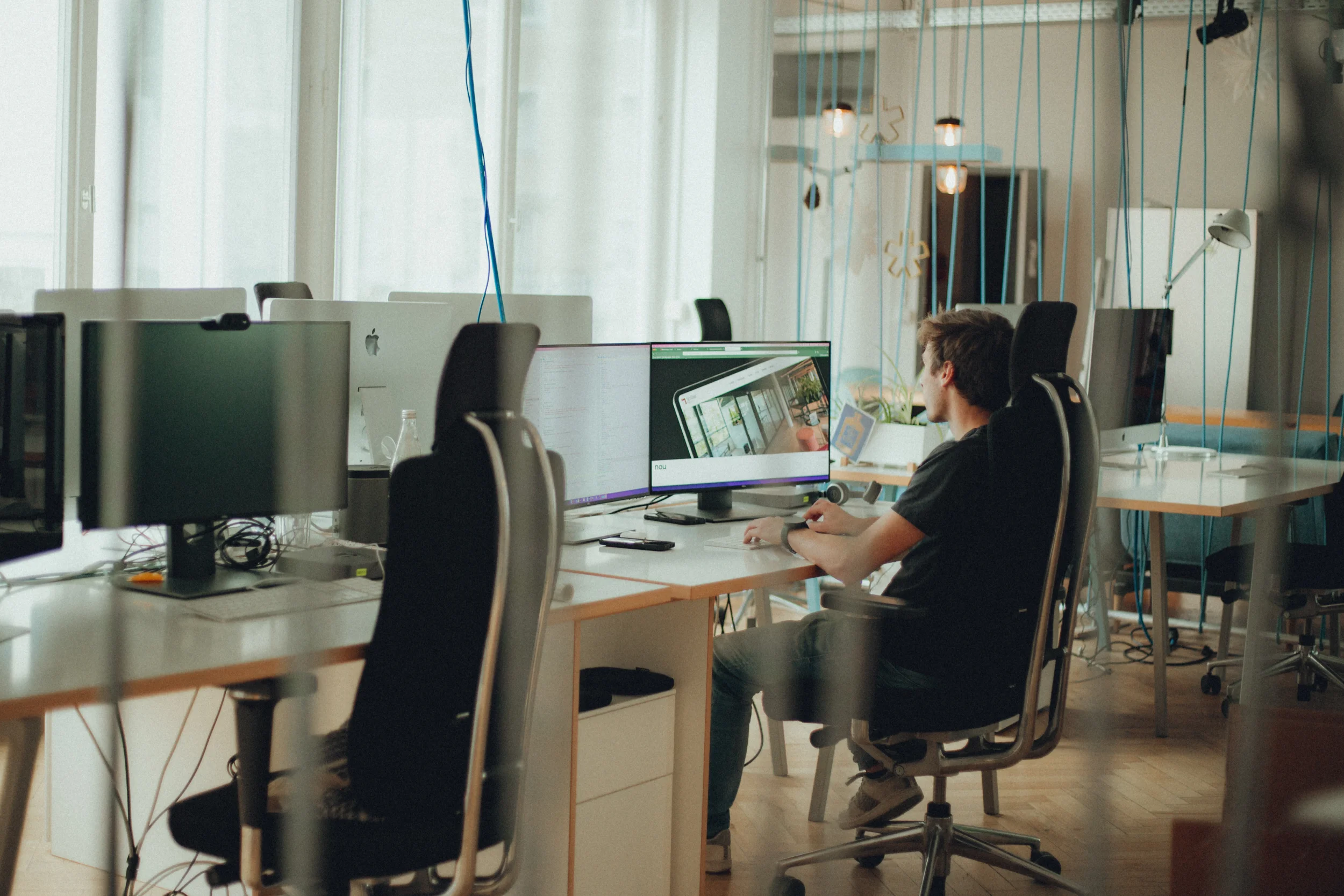 Mitarbeiter arbeitet an einem Computer in einem modernen Büro mit mehreren Arbeitsplätzen