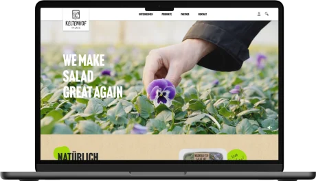 Nahaufnahme eines üppigen Salatfeldes. Ein Arm beugt sich über das satte Grün. Der Slogan „WE MAKE SALAD GREAT AGAIN“ strahlt Frische und Vitalität aus.